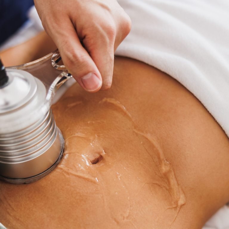 Unrecognizable woman getting an an ultrasound cavitation treatment to fat reduction on abdomen at the beauty salon.